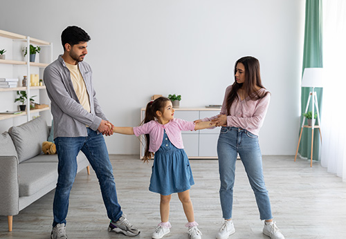 Mother and father holding hands with young daughter representing child custody rights.