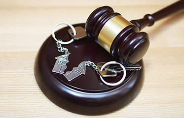 Judge gavel and key ring in shape of two splitted part of house on wooden background. Concept of real estate auction or dividing house when divorce, division of property and real estate, law system.