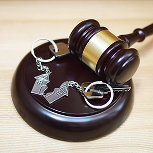 Judge gavel and key ring in shape of two splitted part of house on wooden background. Concept of real estate auction or dividing house when divorce, division of property and real estate, law system.